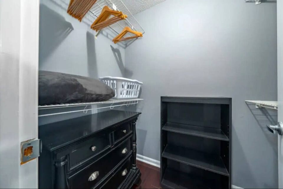 Luxurious master bedroom featuring a king‑size bed, upholstered headboard, smart wall‑mounted TV, and a large chest of drawers. The walk‑in closet offers ample storage, and enjoy direct access to the ensuite bathroom for added privacy and comfort.