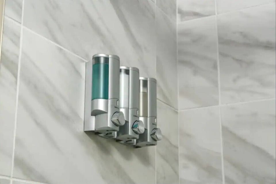 Master ensuite bathroom with a spacious walk‑in shower with sliding glass doors, toilet, sink, and vanity. Stocked with fresh towels, basic toiletries, and a shampoo/conditioner/body wash trio dispenser for a hotel‑style experience.