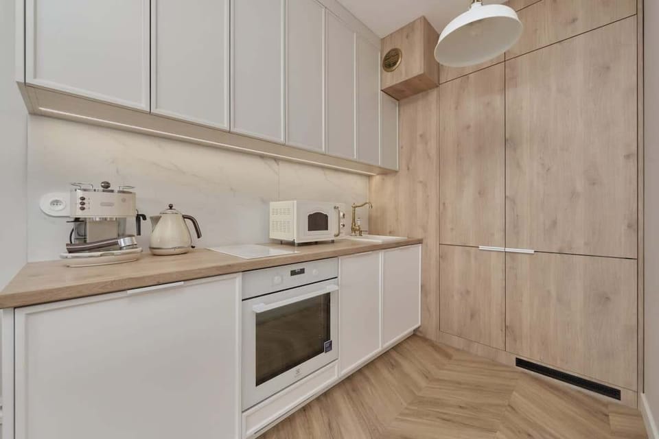 A sleek kitchen with white cabinets, wooden accents, and built-in appliances for a seamless look.