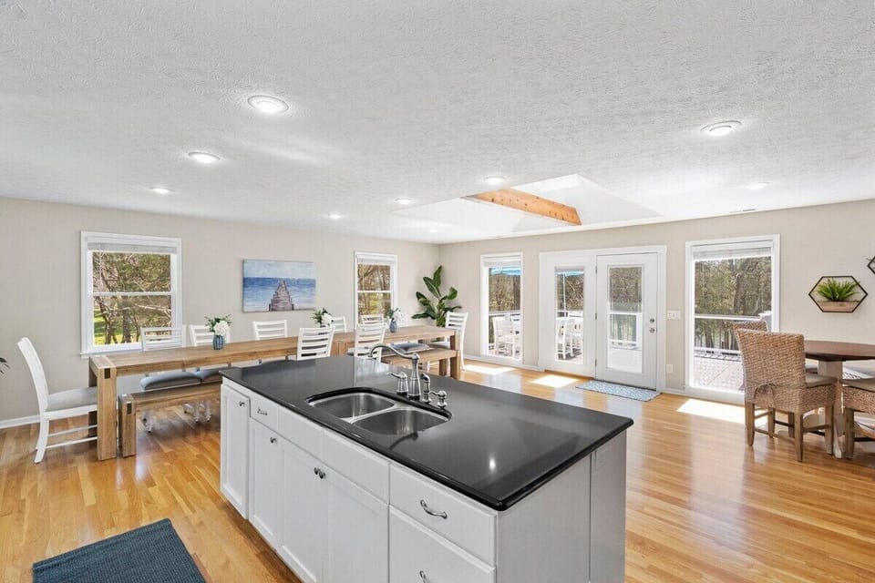 Kitchen sink is stationed in a large Island, ideal for food preparation. Drawers are full of kitchen utensils and cutlery tools. 