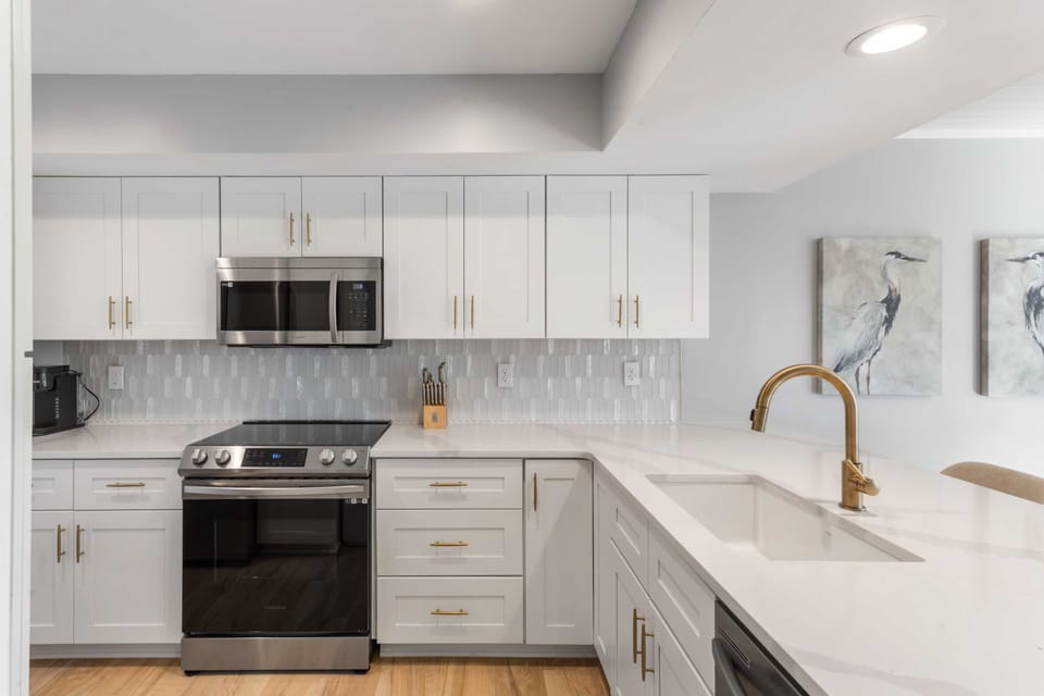 The kitchen is a chef's delight, with quartz counters, stainless steel appliances, shaker cabinets, and a tile backplash.
