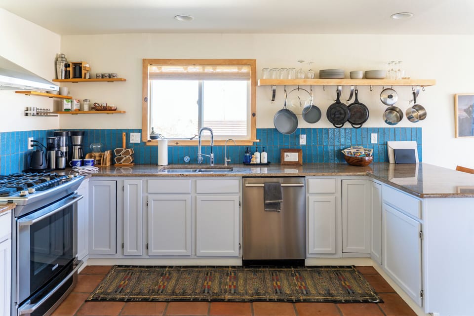 Bright, chef-ready kitchen with blue tile, open shelves, and gas range
