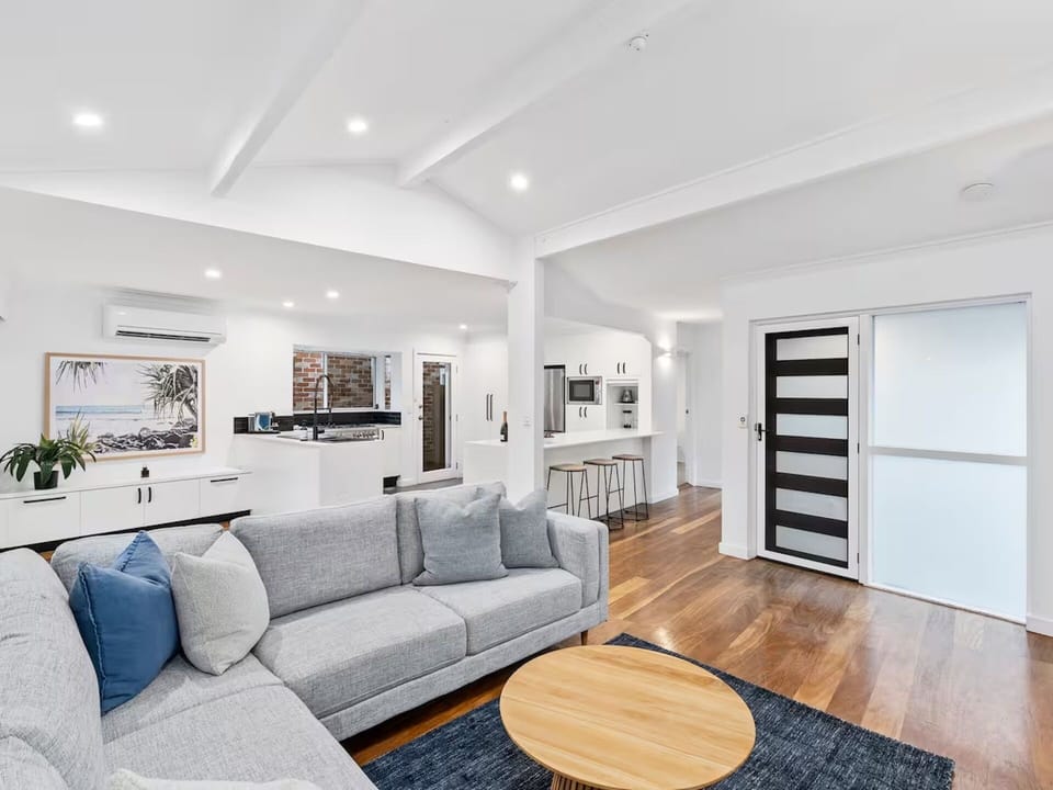 Bright open-plan living space with plush seating, large Smart TV.