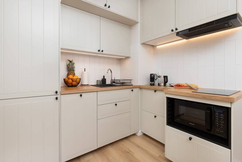 A well-equipped white kitchen with a built-in oven, wooden countertops, and modern appliances.