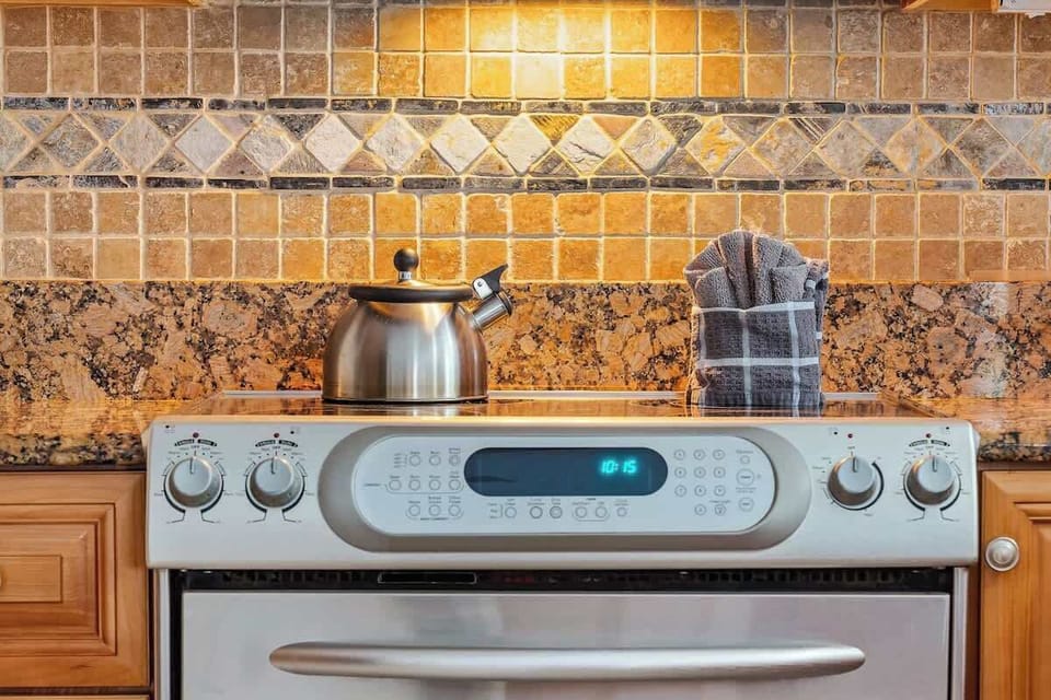 Modern kitchen details designed for everyday comfort. Sleek stainless steel oven, stylish tile backsplash, and granite counters perfect for preparing home-cooked meals, or enjoying a relaxed cooking experience during your stay.