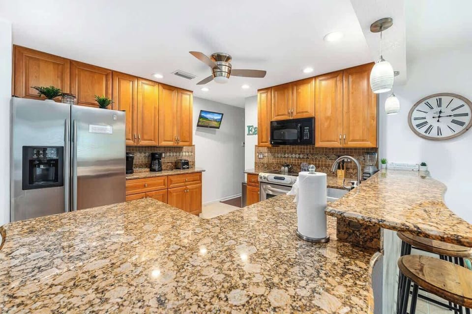 Spacious, sunlit kitchen with granite countertops and stainless steel appliances. Designed for cooking and gathering, it offers generous prep space, modern finishes, and a warm, open layout perfect for shared meals, and easy entertaining.