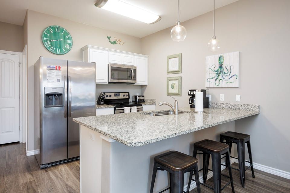 Your fully equipped kitchen features granite countertops, stainless steel appliances, and a breakfast bar perfect for morning coffee or casual meals.