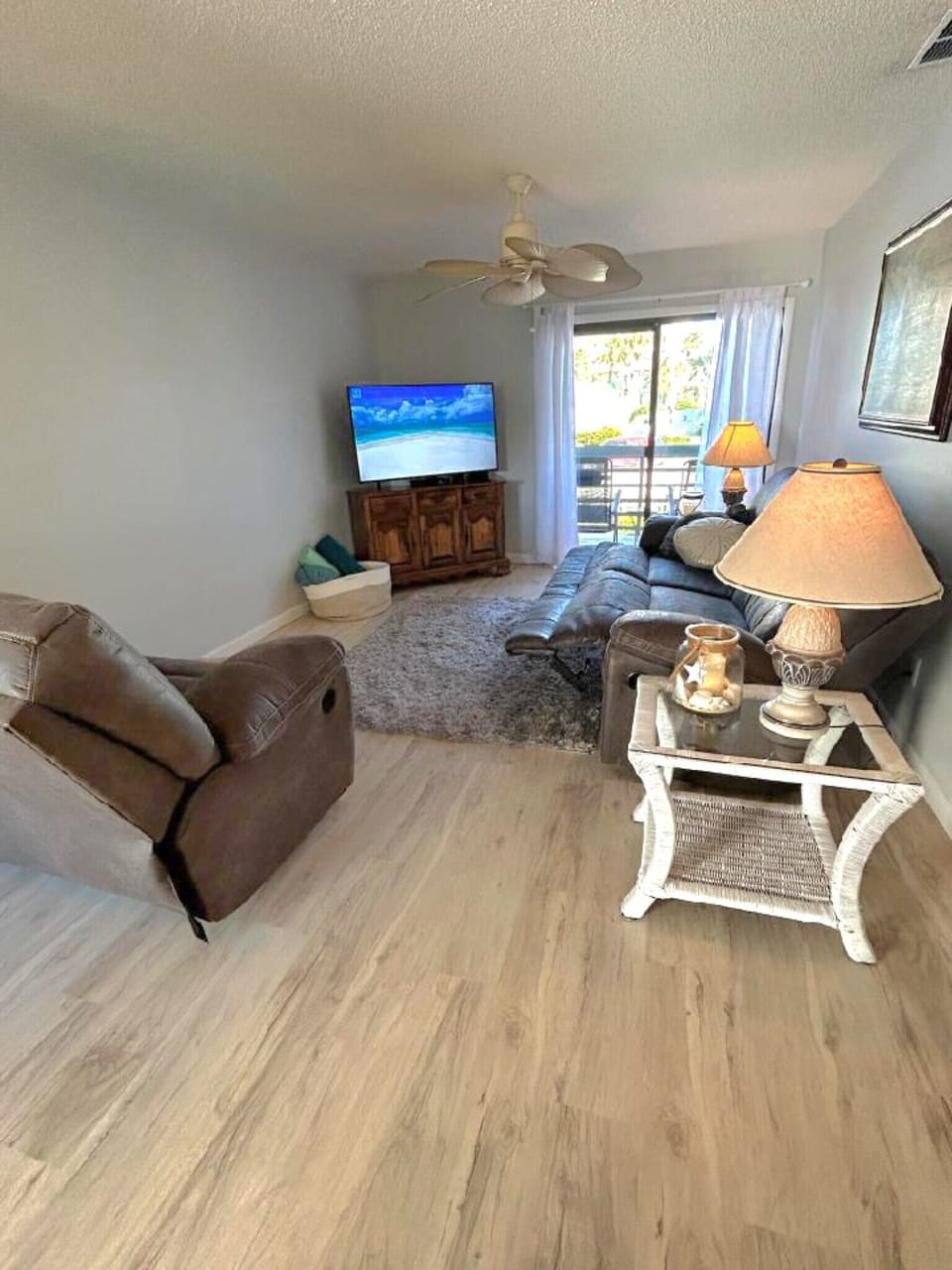 Living room has a comfy couch with leg rests and a lazy boy, lgr screen TV,patio