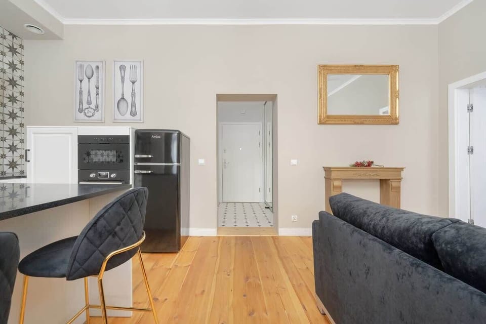 A stylish living area with a modern sofa, a TV stand, and a kitchenette with open shelving.