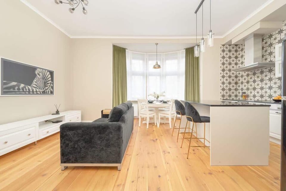 A stylish living area with a modern sofa, a TV stand, and a kitchenette with open shelving.