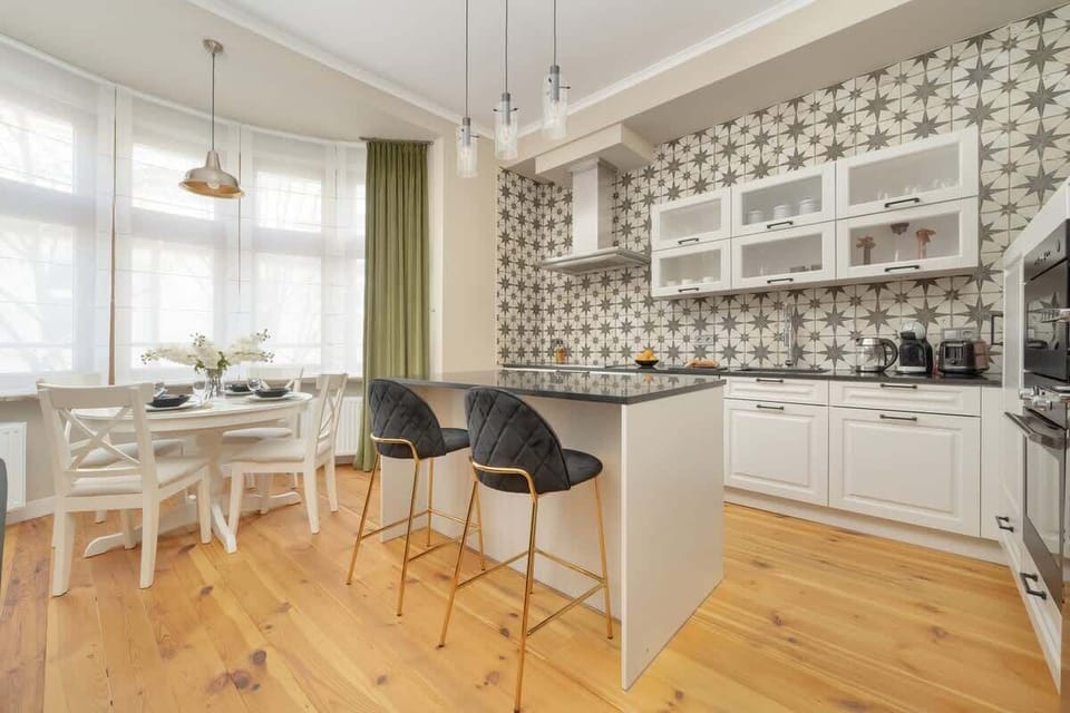 A modern open-concept space with a sitting area and a kitchenette featuring stylish backsplash tiles.