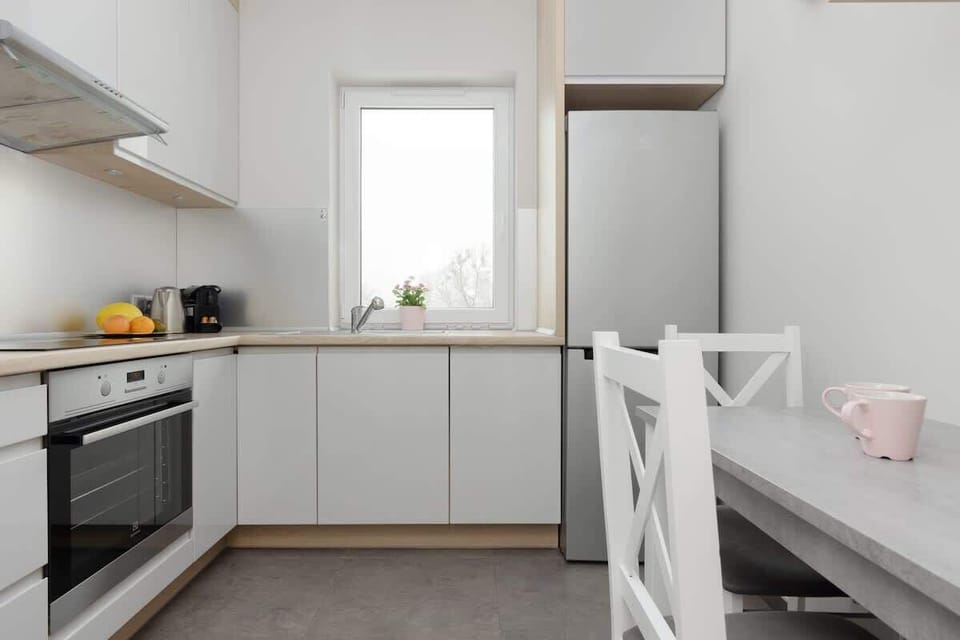 A bright and modern kitchen with white cabinets, a built-in oven, and a minimalist design. The kitchen looks clean and functional.
