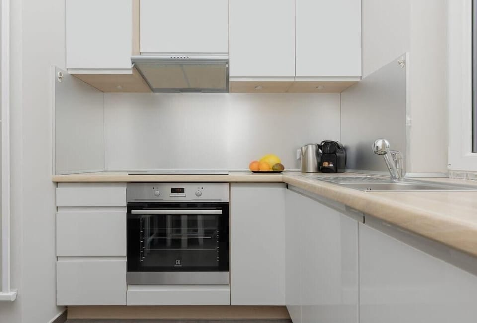 A bright and modern kitchen with white cabinets, a built-in oven, and a minimalist design. The kitchen looks clean and functional.