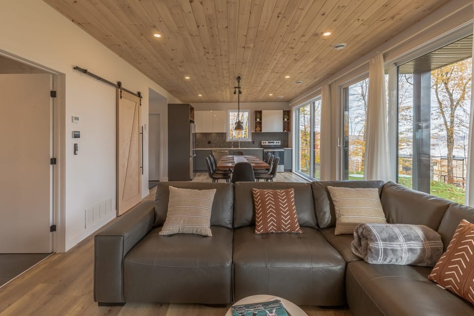 Sectional sofa in open-plan living space with forest views