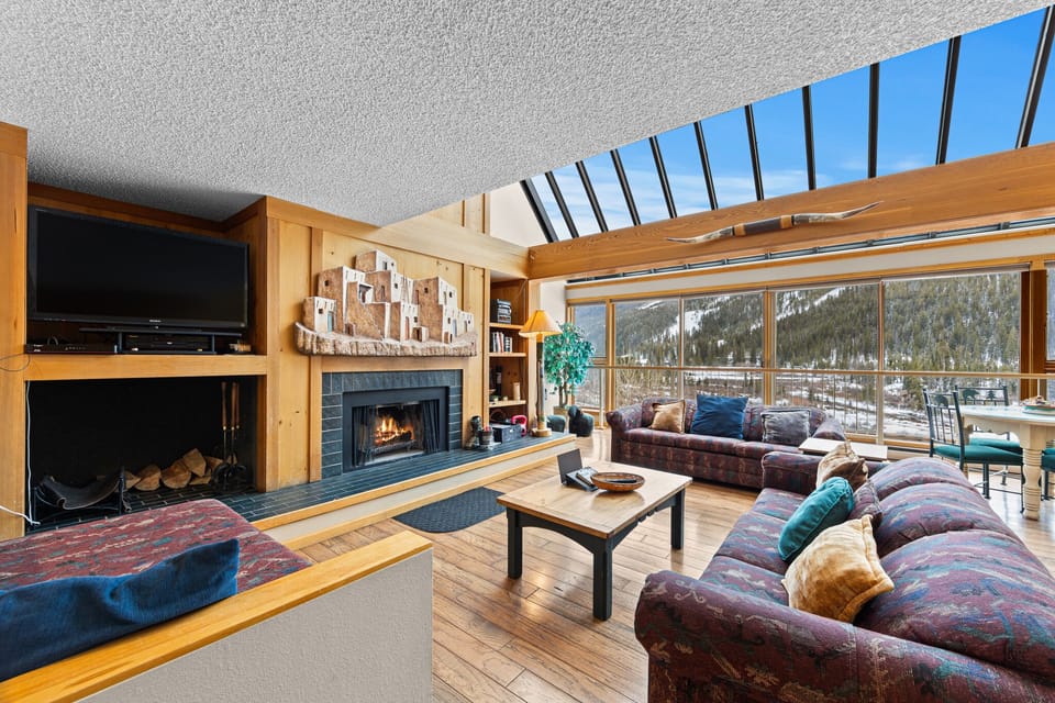 Relax in your spacious living room with crackling fireplace, soaring ceilings, and stunning mountain views through floor-to-ceiling windows.