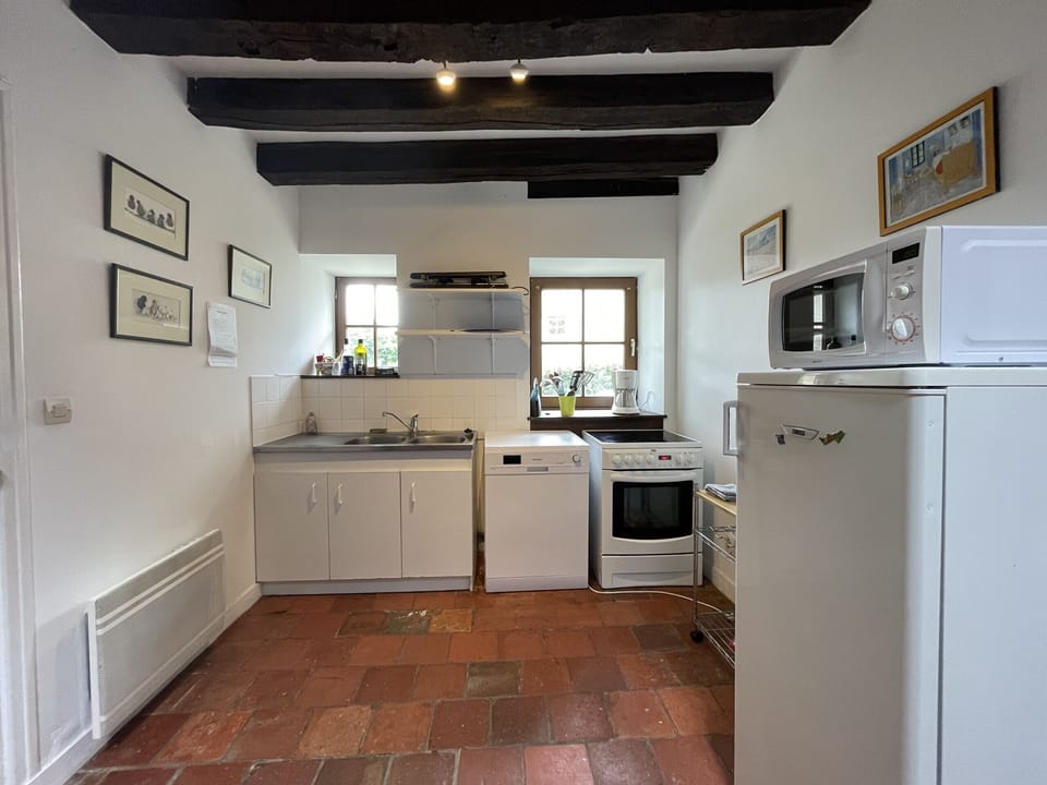 "This open plan kitchen is fully equipped and furnished, with all the kitchen essentials at your disposal. It rests on a red terracotta floor, with white walls and natural wooden beams for a warm atmosphere."