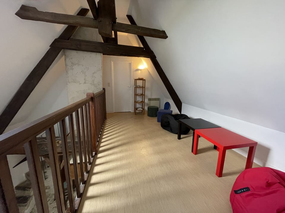 "This hall located at the top of the stairs offers a comfortable transition space to the bedrooms. A small coffee table is placed in the center of the room, surrounded by some relaxing seats. This space is ideal for a peaceful break or to plan the day ahead."