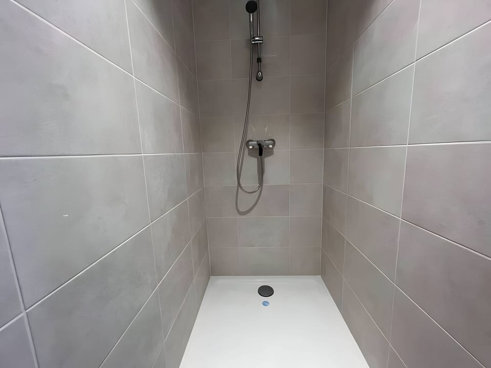 "Discover the fully tiled shower in the "Le Donjon" apartment. Enjoy the elegance and style of this modern, spacious shower."