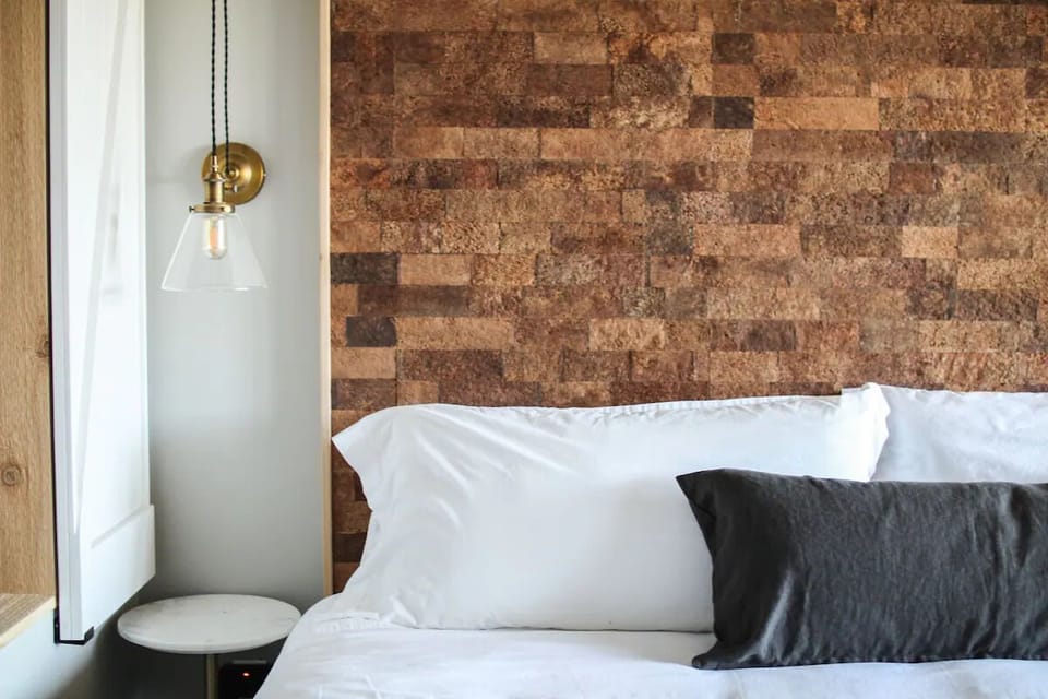 Feel boutique comfort with statement wall and glowing bedside pendant.