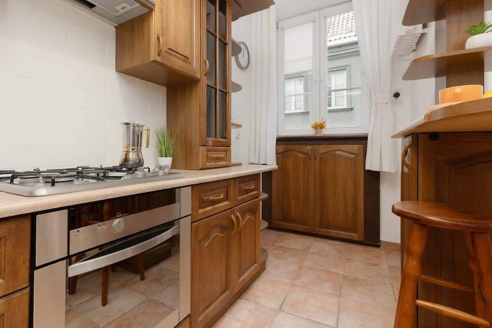 A spacious kitchen with wooden cabinets, built-in appliances, and a tiled floor.

