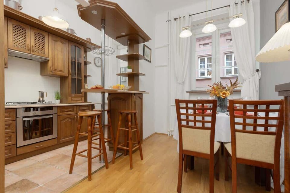 A traditional dining area with wooden furniture and a large kitchen in the background.

