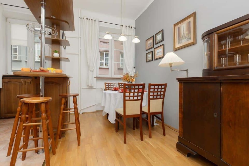 A traditional dining area with high chairs, a bar counter, and vintage artwork.







