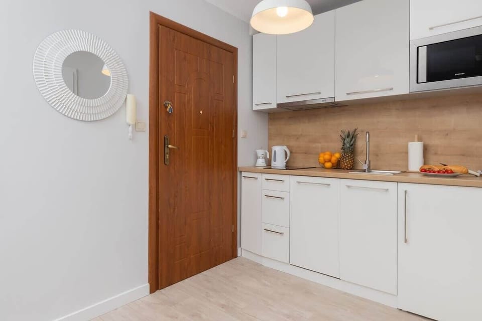 A full kitchen setup with white cabinetry, a wooden door, and coastal-themed decor, blending style and utility.






