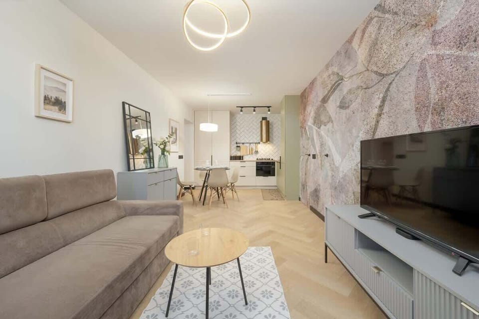 A spacious living and dining area with a modern chandelier and elegant furnishing.
