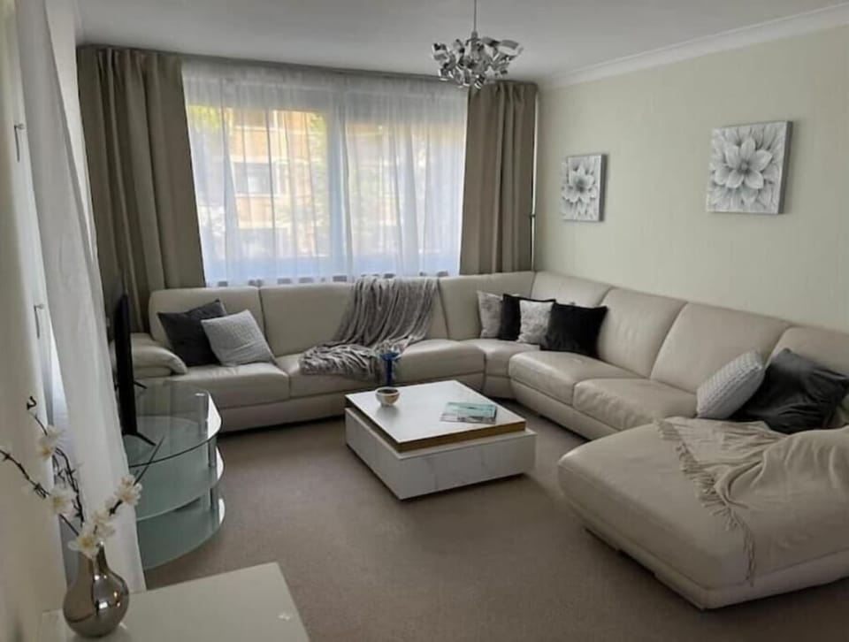 Living area with extra large corner sofa, wifi-enabled TV and large windows.