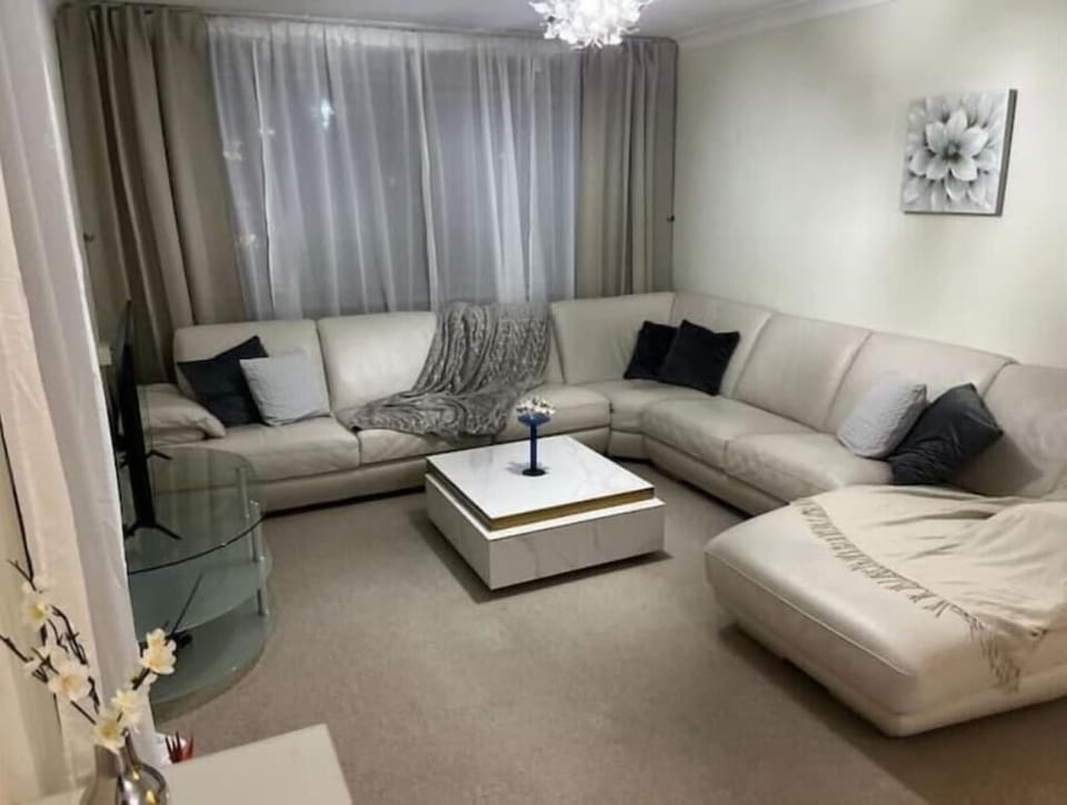 Living area with extra large corner sofa, wifi-enabled TV and large windows.