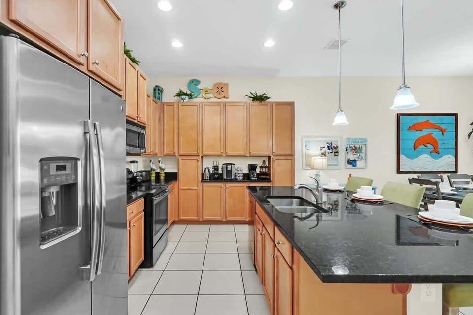 Modern kitchen with stainless steel appliances and a large black granite island for family-friendly meals.