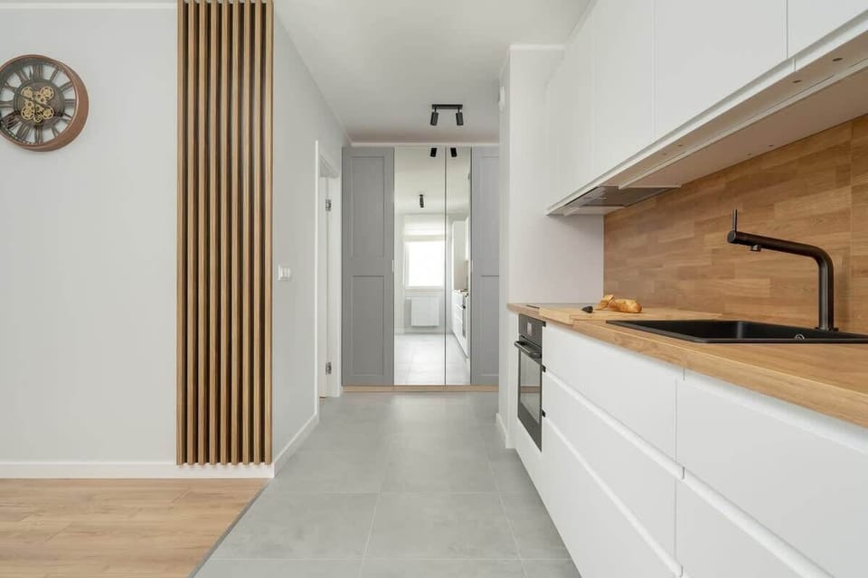 A kitchen and dining area with a large wooden table, elegant chairs, and bright lighting.
