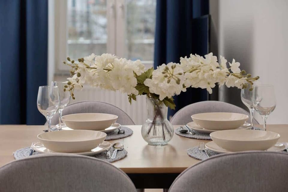A beautifully arranged dining table with elegant plates, glasses, and a floral centerpiece, perfect for a delightful dining experience.
