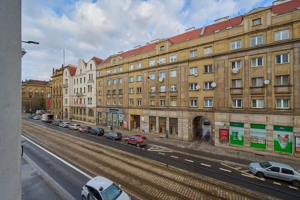 A vibrant street view capturing colorful historic buildings, busy roads, and trams passing by, showcasing the lively urban environment.
