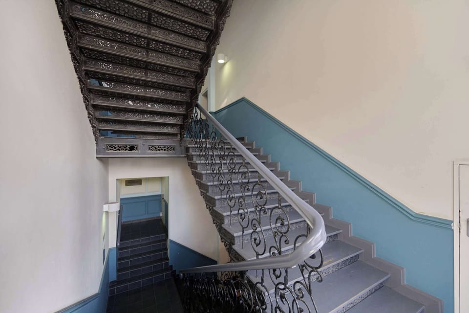 The decorative staircase with an ornate cast-iron balustrade and carefully preserved architectural details leads to the apartments, highlighting the character of the place and adding a sense of prestige to everyday returns.