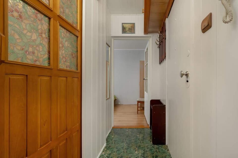 A hallway with wooden panels, decorative glass, and doors leading to various parts of the apartment, adding character to the space.







