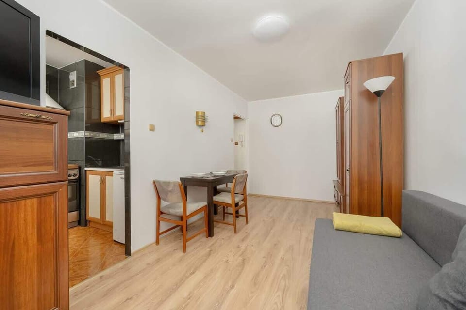 A different perspective of the dining area with a wooden cabinet, chairs, and an open space connecting to the living room.

