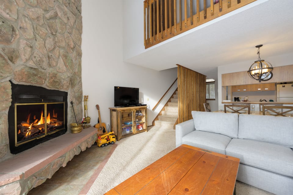 Cozy up by the crackling stone fireplace in your inviting living space, complete with comfortable seating and warm wood accents throughout.