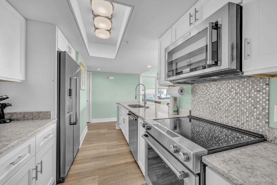 Step into your gourmet galley kitchen with gleaming granite countertops, sparkling mosaic backsplash, and premium stainless steel appliances ready for your culinary adventures.