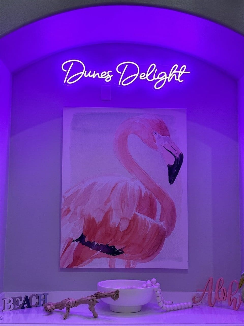 Designer accent bedroom with neon-style wall sign and custom coastal décor.