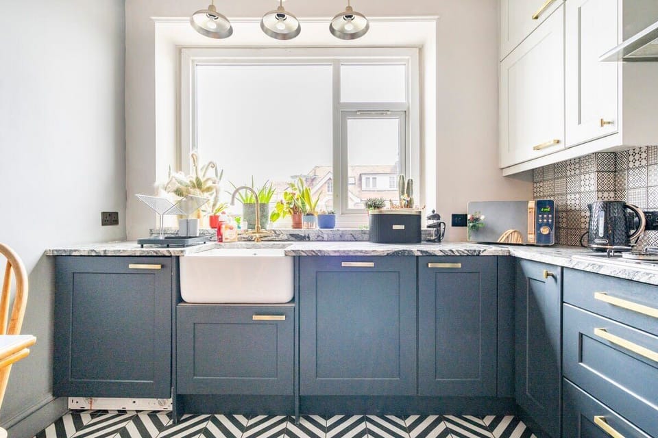 A small yet beautiful navy blue and marble counter-topped kitchen
