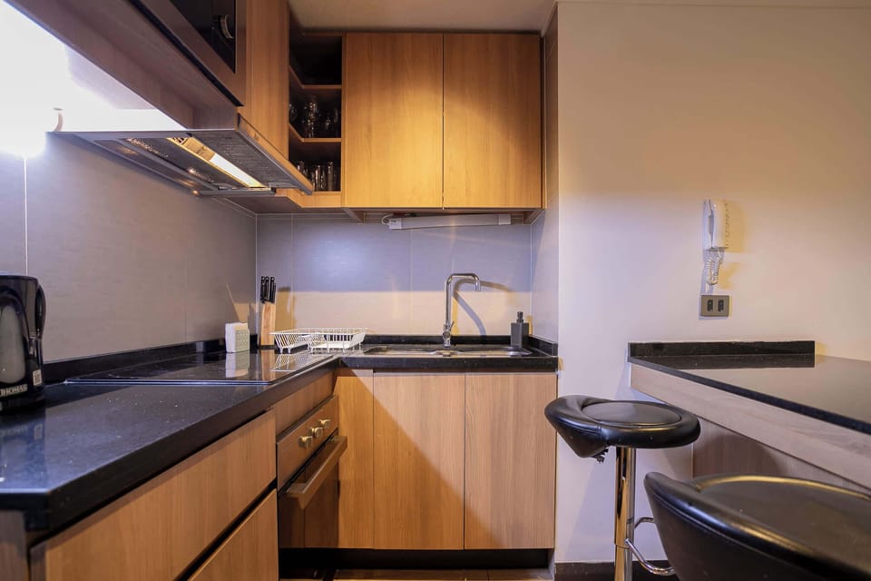 Modern kitchen with sleek wooden cabinets and a cozy breakfast bar, perfect for enjoying a meal in your home away from home.