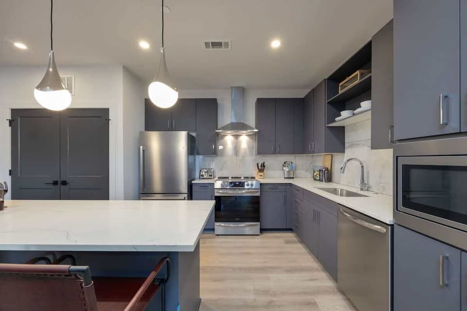 Fully equipped kitchen stocked with basic cooking essentials, stainless steel appliances, and breakfast bar seating, all connected to the dining area.