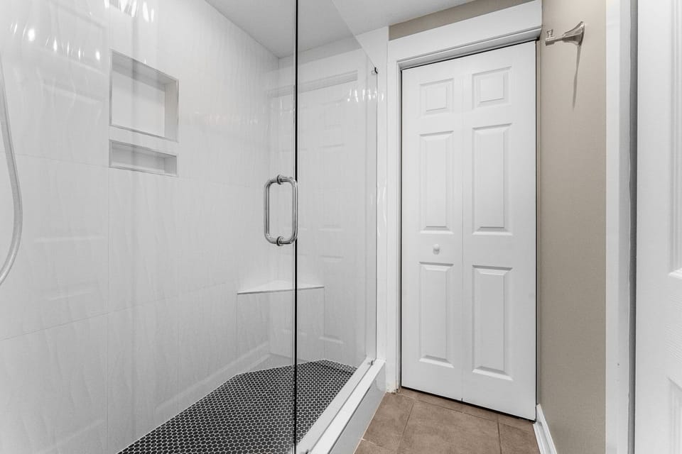 Modern walk-in shower with glass enclosure and built-in bench.