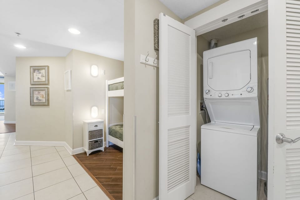 Compact laundry area with stacked washer and dryer next to a cozy bunk bed space.