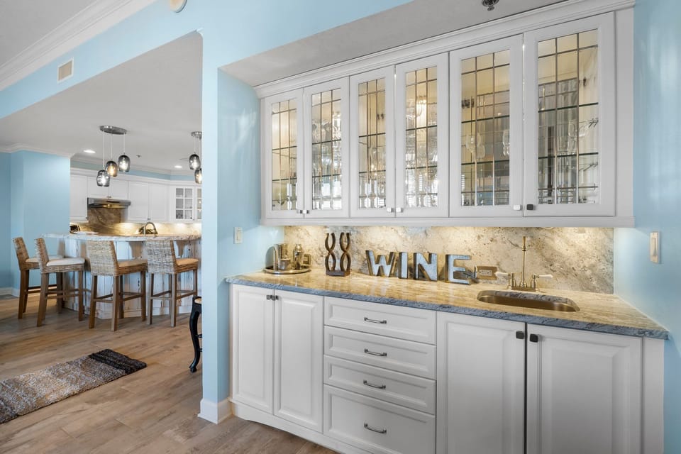 Modern kitchen area with glass-front cabinets and a marble backsplash