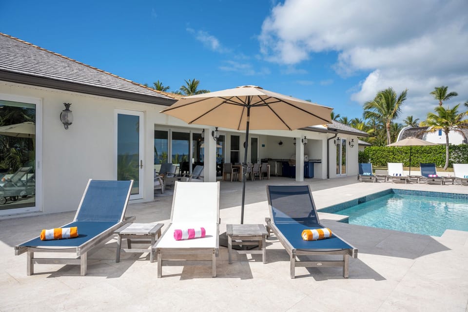 The patio is furnished for lounging and dining, features an outdoor kitchen with a gas grill.