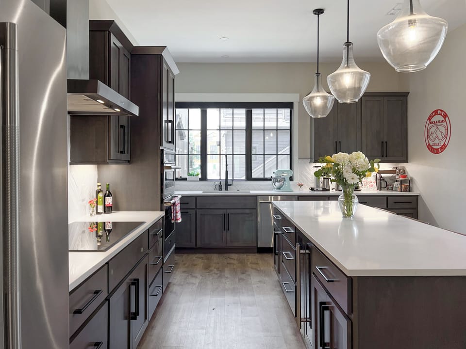 - Bright kitchen features dark cabinetry, oversized island, and chic lighting - Prep meals with ease on the long counters and essential appliances - Enjoy cooking in a space that’s both functional and beautifully designed