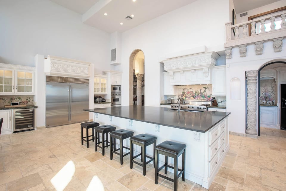 Spacious kitchen with dark island, stainless steel appliances, and balcony.