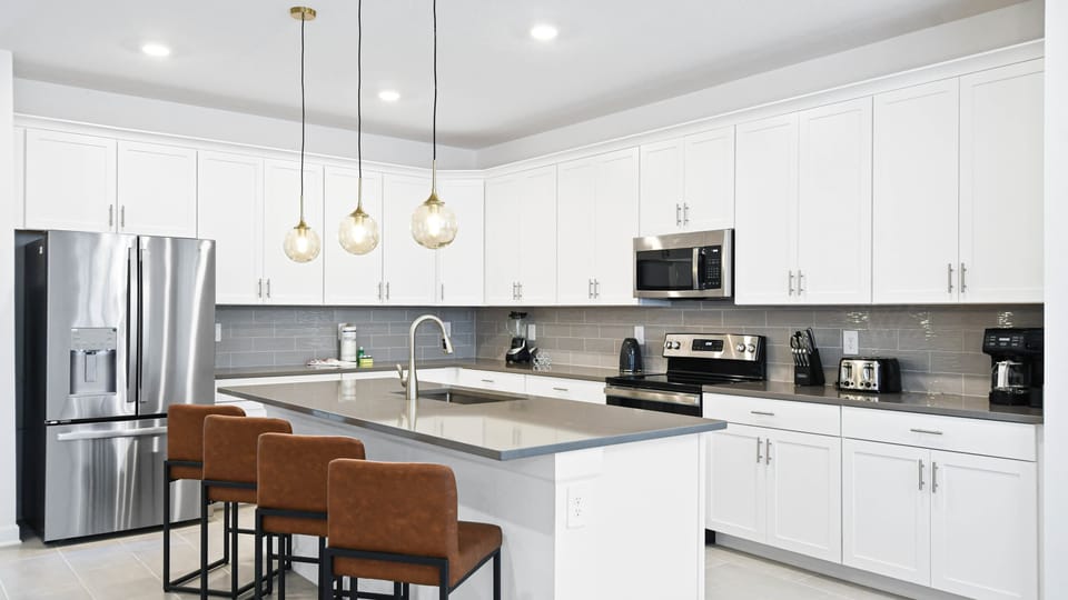 Sleek modern kitchen with stainless steel appliances, large island, and pendant lights.